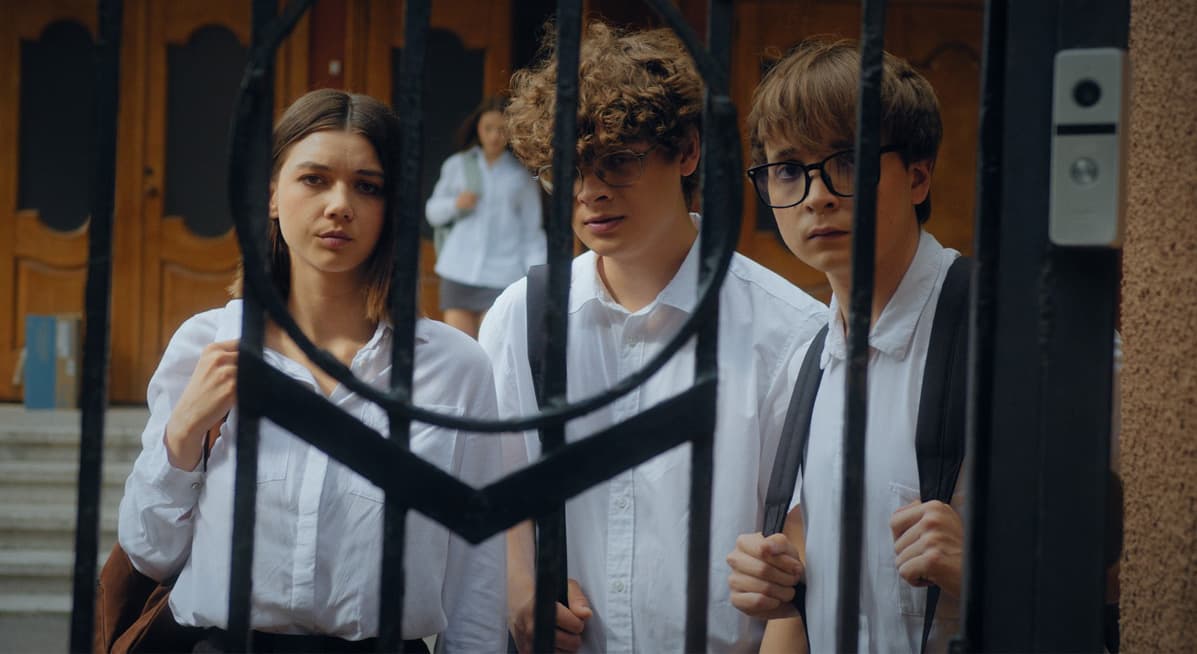 Перший кадр із фільму «Я граю»: підлітки тривожно дивляться крізь залізні ворота.